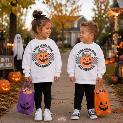 Girl and boy wearing white Halloween sweatshirts with I Take Candy From Strangers pumpkin graphic while trick-or-treating with candy bags.