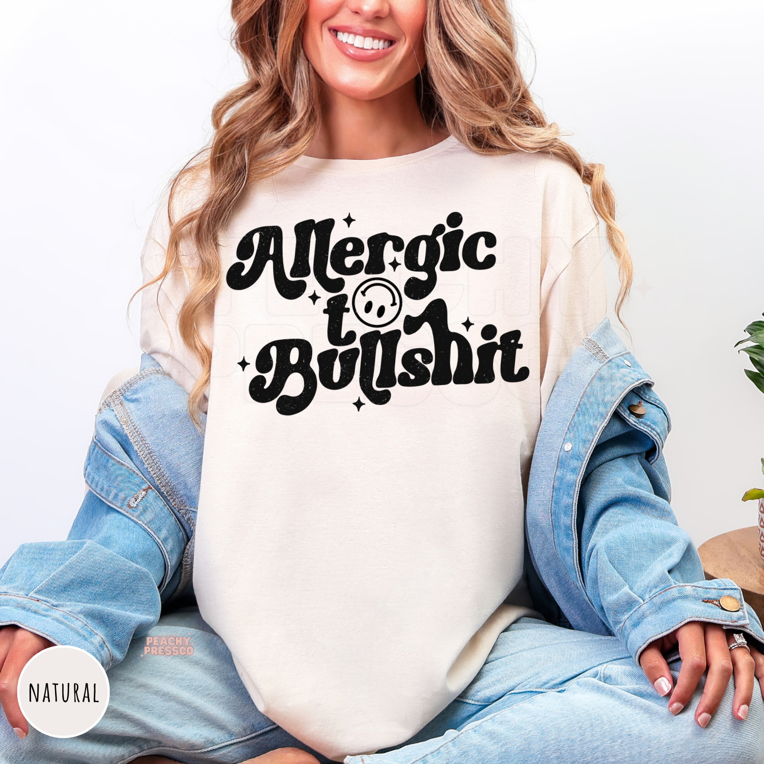 Natural t-shirt featuring a bold distressed "Allergic to Bullshit" retro graphic with smiley face. Humorous unisex graphic tee perfect for everyday outfits.