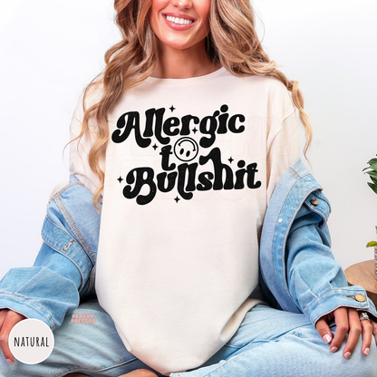 Natural t-shirt featuring a bold distressed "Allergic to Bullshit" retro graphic with smiley face. Humorous unisex graphic tee perfect for everyday outfits.
