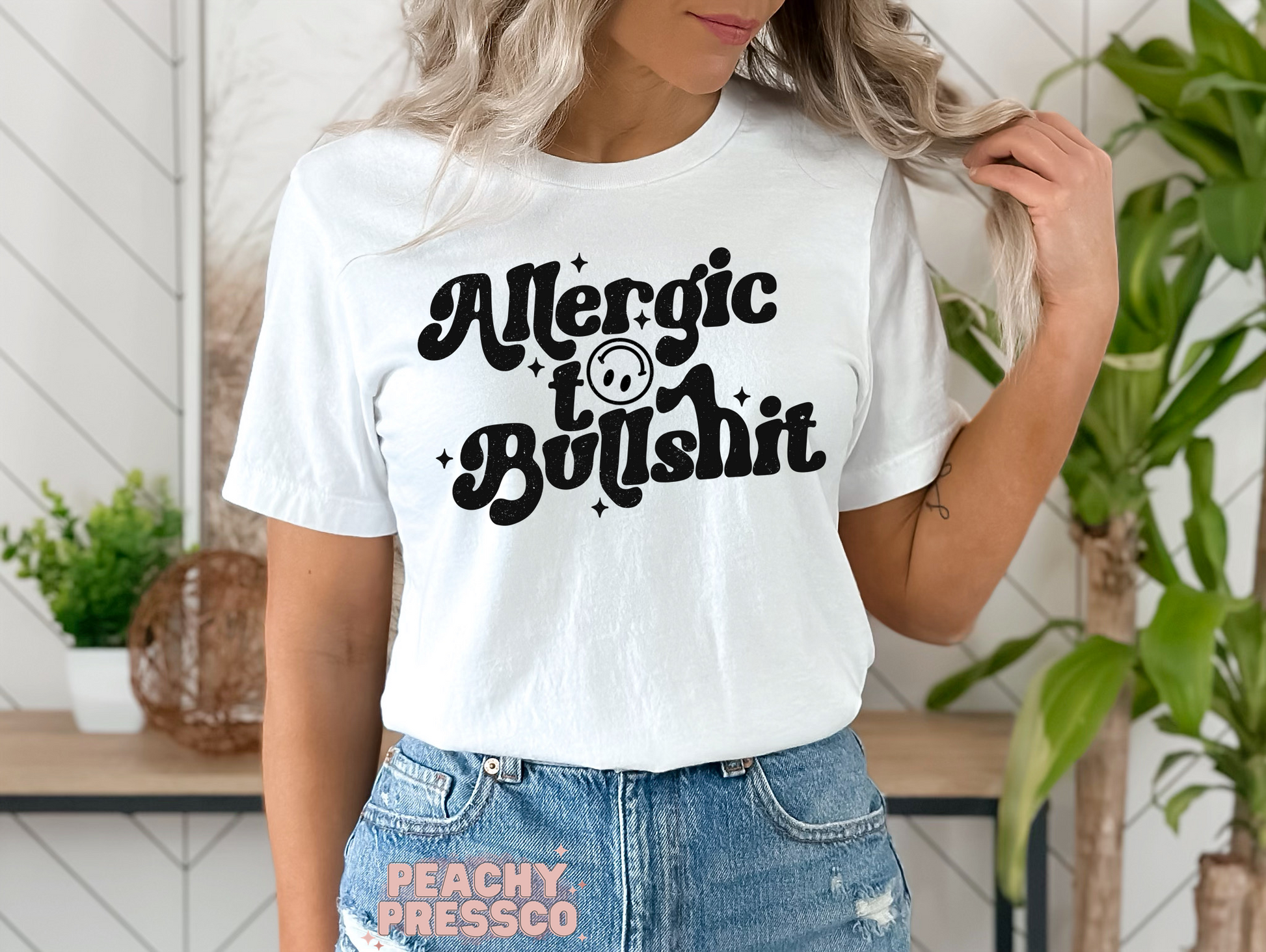 White unisex t-shirt featuring a vintage "Allergic to Bullshit" graphic with distressed retro lettering and smiley face. Funny sarcastic graphic tee for men and women.