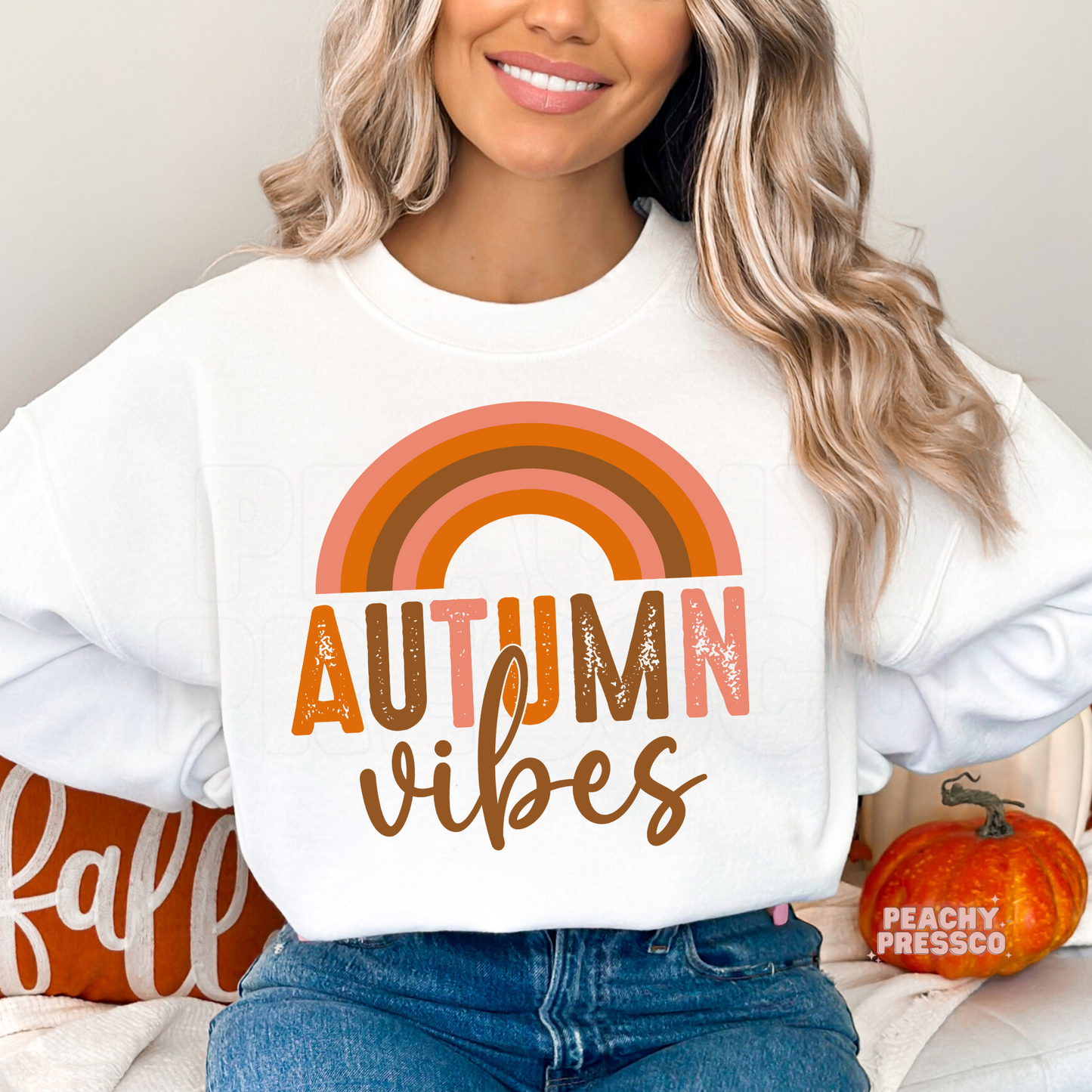 Woman wearing a white crewneck sweatshirt with a colorful retro rainbow Autumn Vibes graphic for cozy fall fashion.