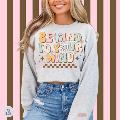 Ash grey Be Kind to Your Mind sweatshirt featuring pastel pink, blue, yellow and sage green lettering with smiling daisies and a retro checkerboard accent.