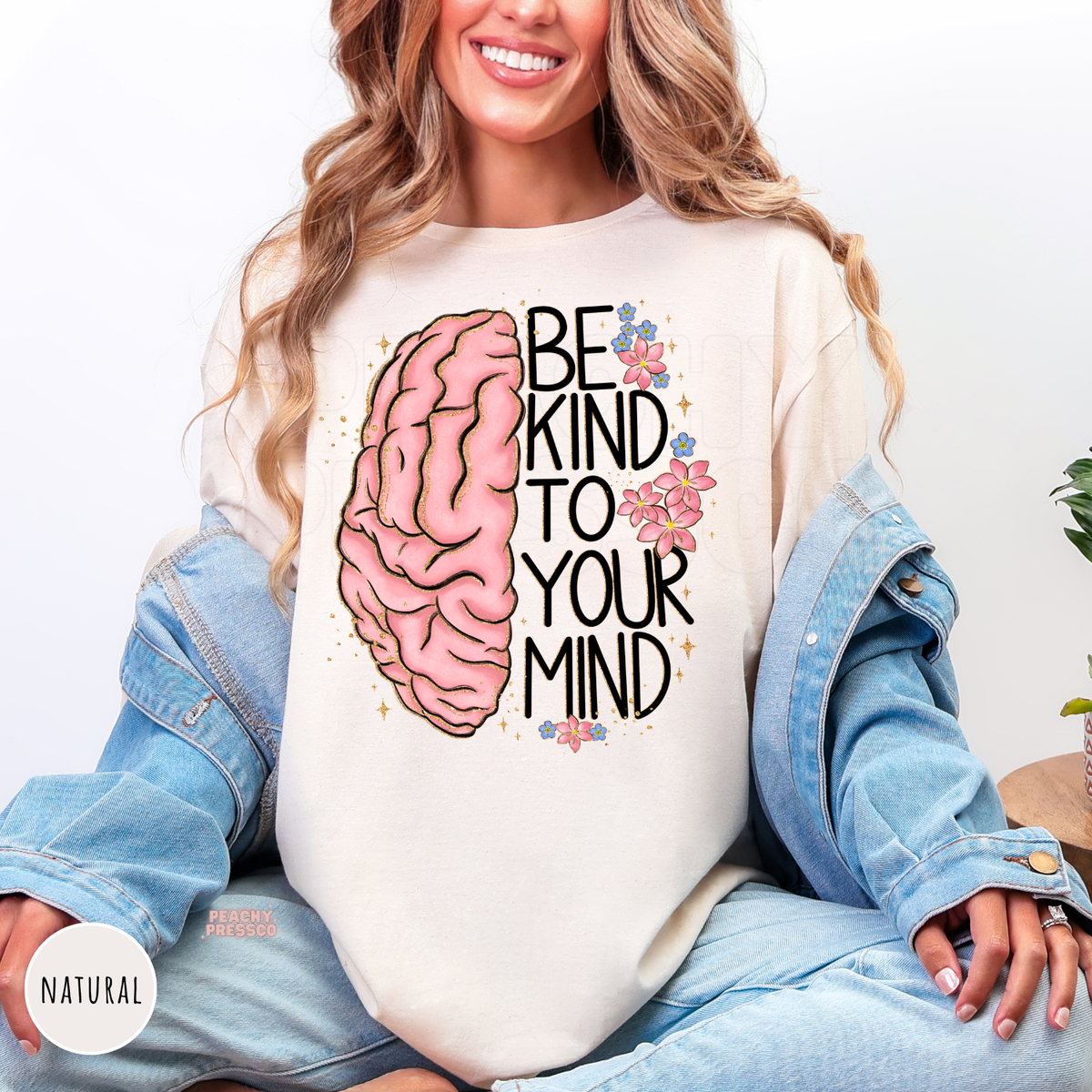 Natural shirt featuring a pink brain illustration with flowers and the quote "Be Kind to Your Mind," creating a thoughtful mental health awareness design.