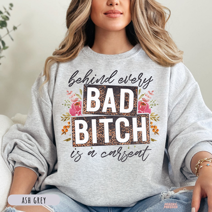Woman wearing an ash grey sweatshirt with behind every bad bitch is a carseat leopard print floral graphic for moms.