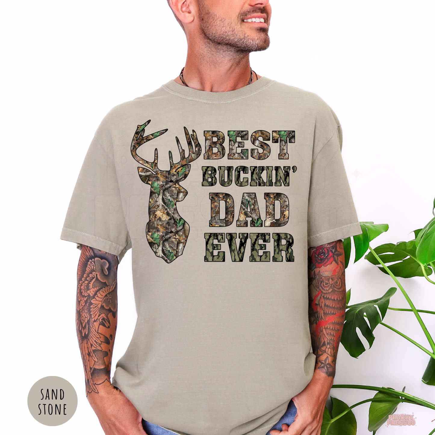 Sandstone Comfort Colors t-shirt with a camouflage buck design and Best Buckin' Dad Ever graphic, ideal for deer hunters and outdoorsmen.