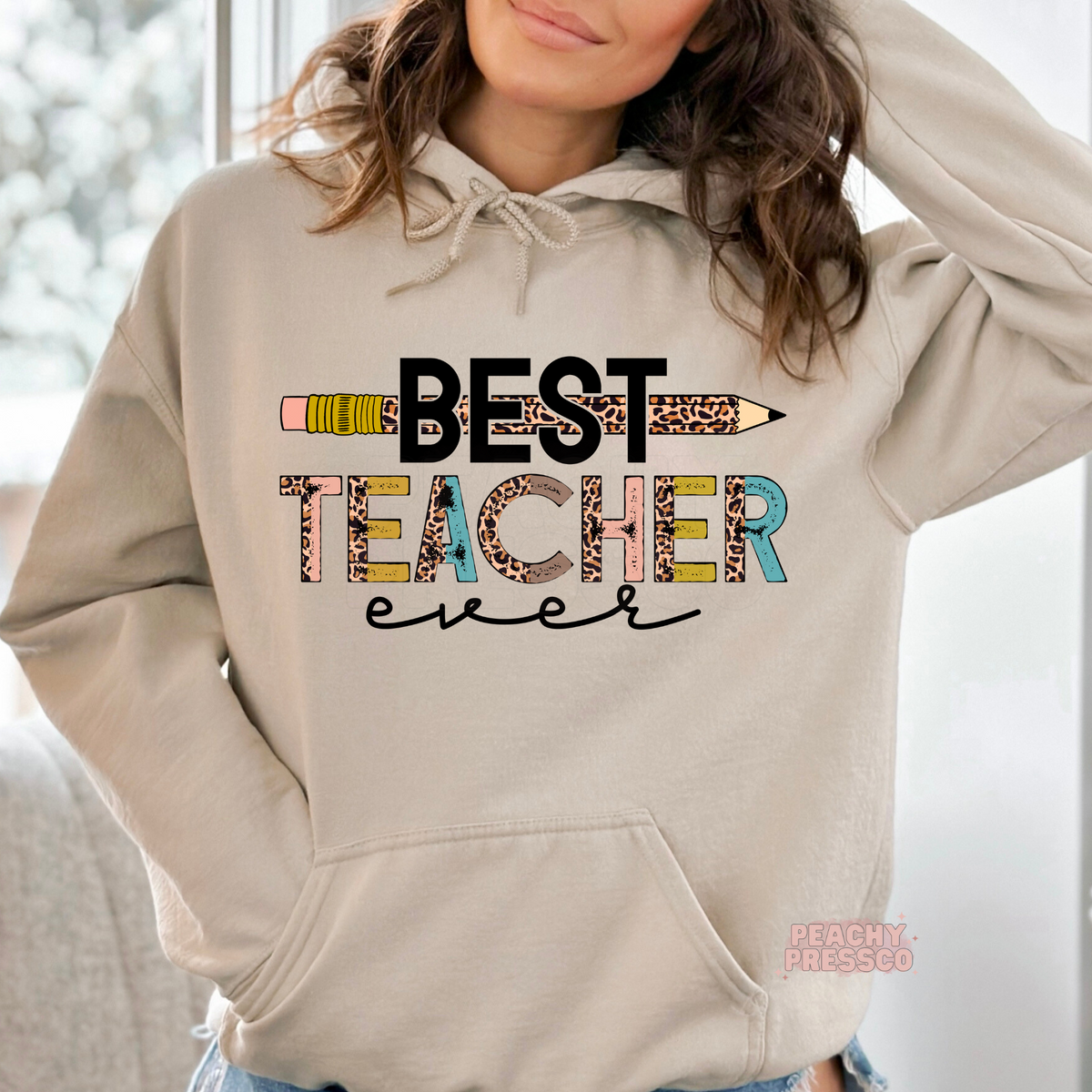Sand teacher hoodie featuring a "Best Teacher Ever" graphic with a leopard print pencil, colorful distressed text, and a stylish back-to-school design.