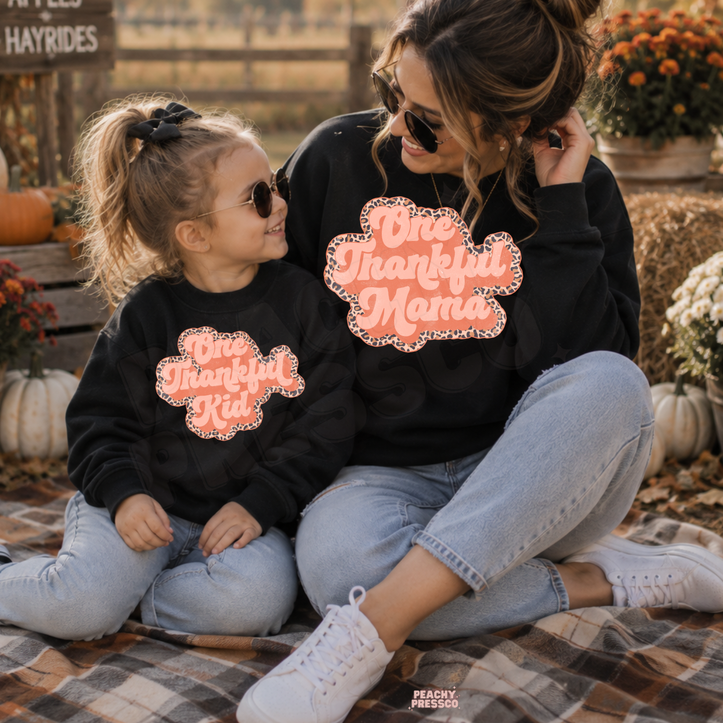 Matching black One Thankful Mama and One Thankful Kid crewneck sweatshirts for mother and daughter enjoying a pumpkin patch in autumn.