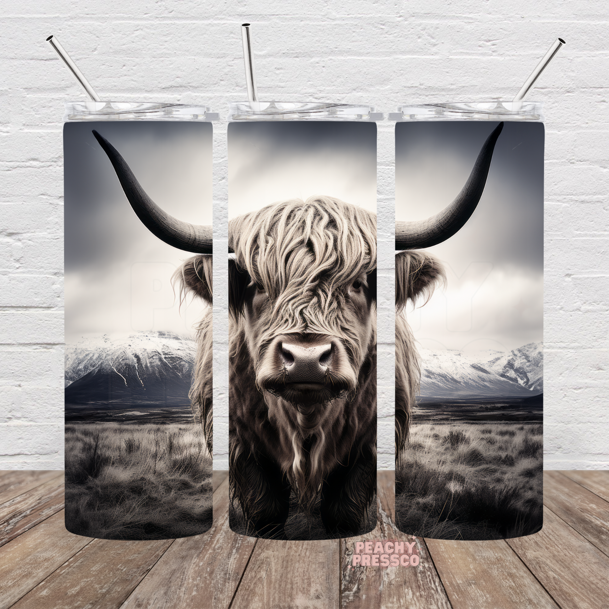 Black and white Highland cow standing before snow-covered mountains on a full wrap 20oz skinny tumbler.