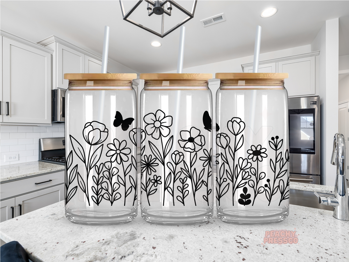 16 oz clear glass cup with minimalist black wildflower illustrations wrapping around the glass. Includes bamboo lid and reusable straw.