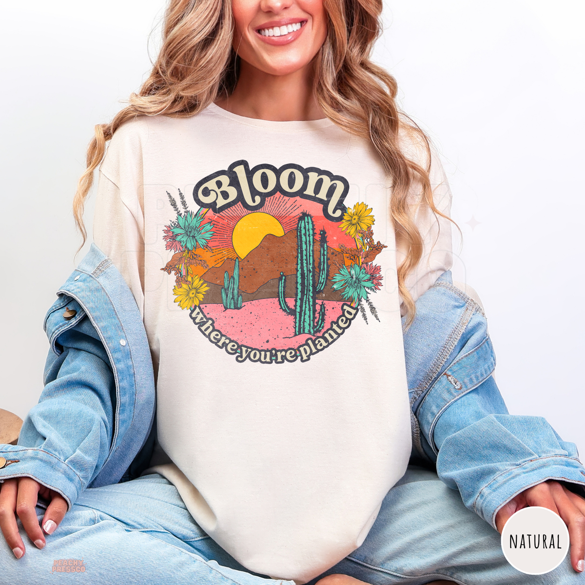 Natural Bloom Where You're Planted shirt featuring a vintage desert cactus illustration, colorful sunset, blooming wildflowers, and motivational quote.