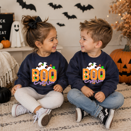 Toddler boy and girl wearing matching navy Boo Crew Halloween sweatshirts with a colorful ghost graphic in a cute Halloween setting.