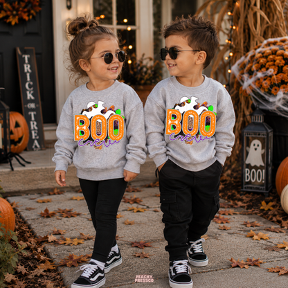 Boy and girl wearing matching sport grey Boo Crew Halloween sweatshirts with a colorful ghost design for a cute sibling Halloween outfit.