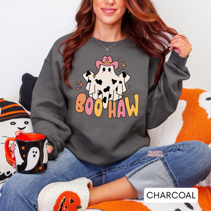 Woman wearing a charcoal Halloween crewneck sweatshirt with a cute cowgirl ghost Boo Haw graphic while holding a ghost mug.