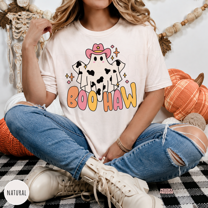 Woman wearing a natural colored Boo Haw Halloween graphic t-shirt with a cute western ghost and colorful lettering.