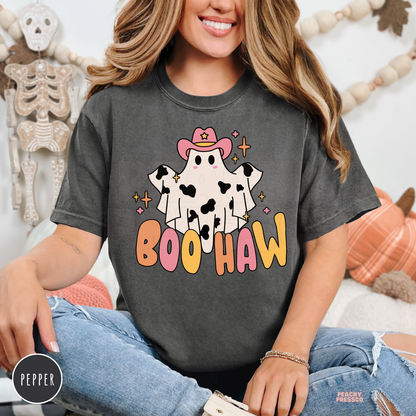 Woman wearing a pepper Comfort Colors Boo Haw Halloween t-shirt featuring a cute western ghost and colorful fall lettering.