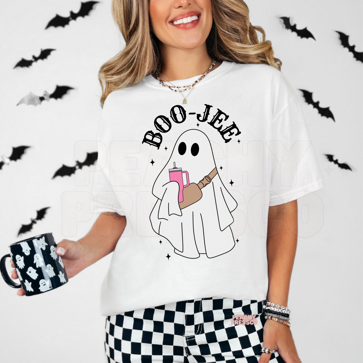 Woman wearing a white Boo-Jee ghost Halloween t-shirt with cute ghost graphic and bats in the background.