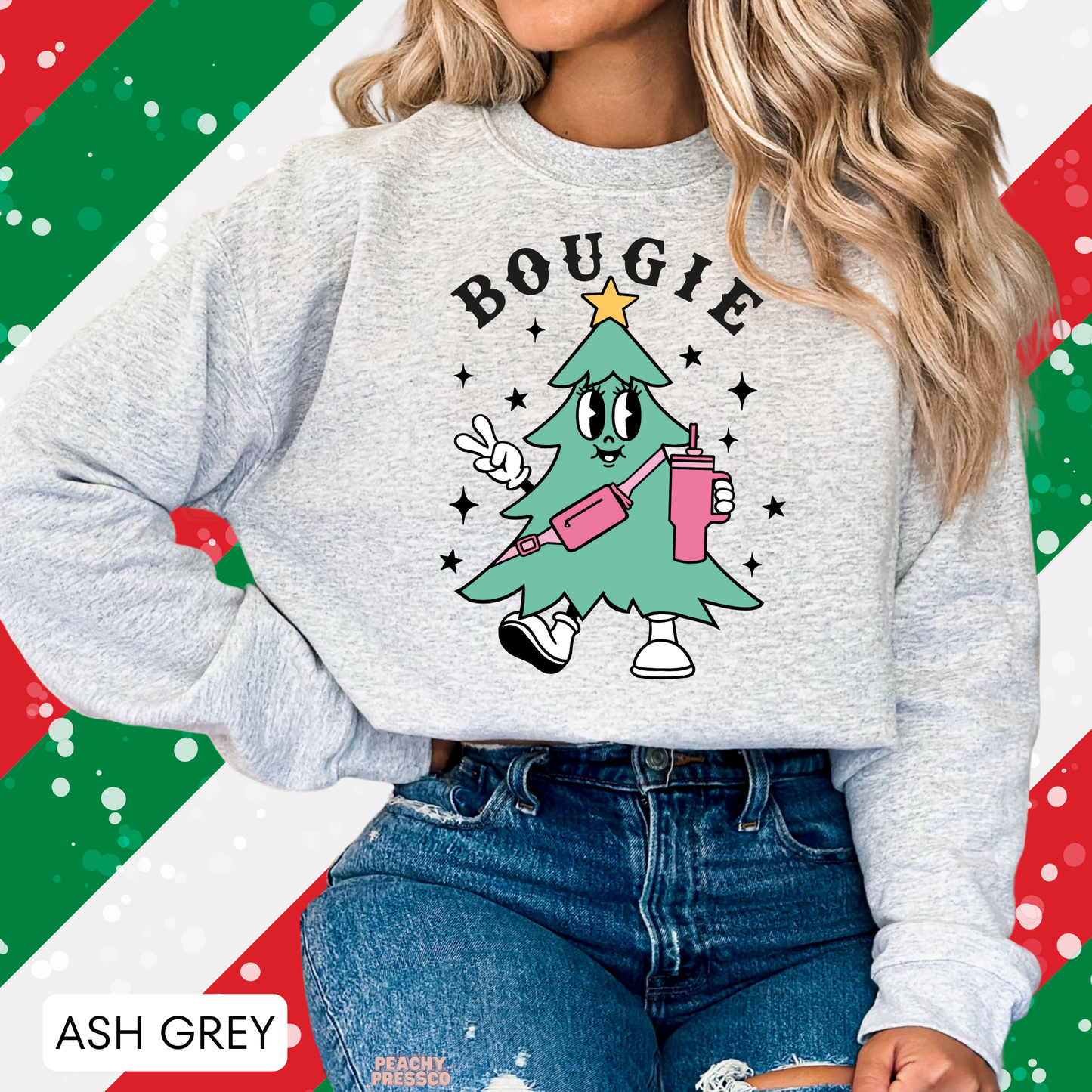 Women wearing an ash grey Bougie Christmas tree sweatshirt in front of a festive green and red striped holiday background.