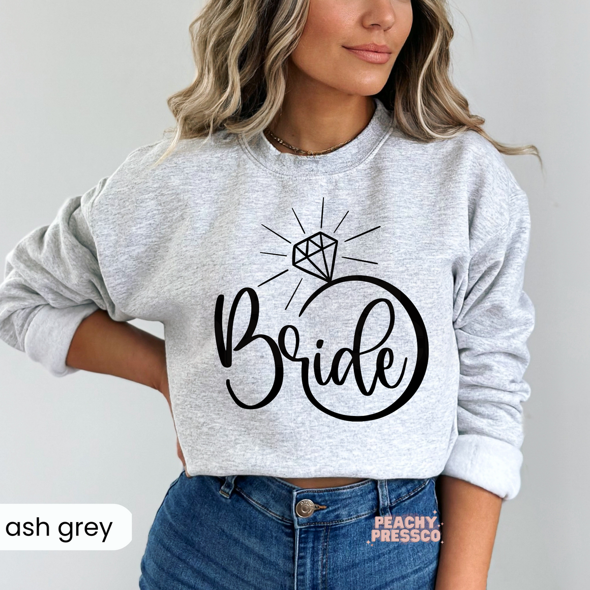 Ash grey crewneck sweatshirt with a modern black "Bride" engagement ring graphic, ideal for brides-to-be, bridal weekends, and honeymoon travel.