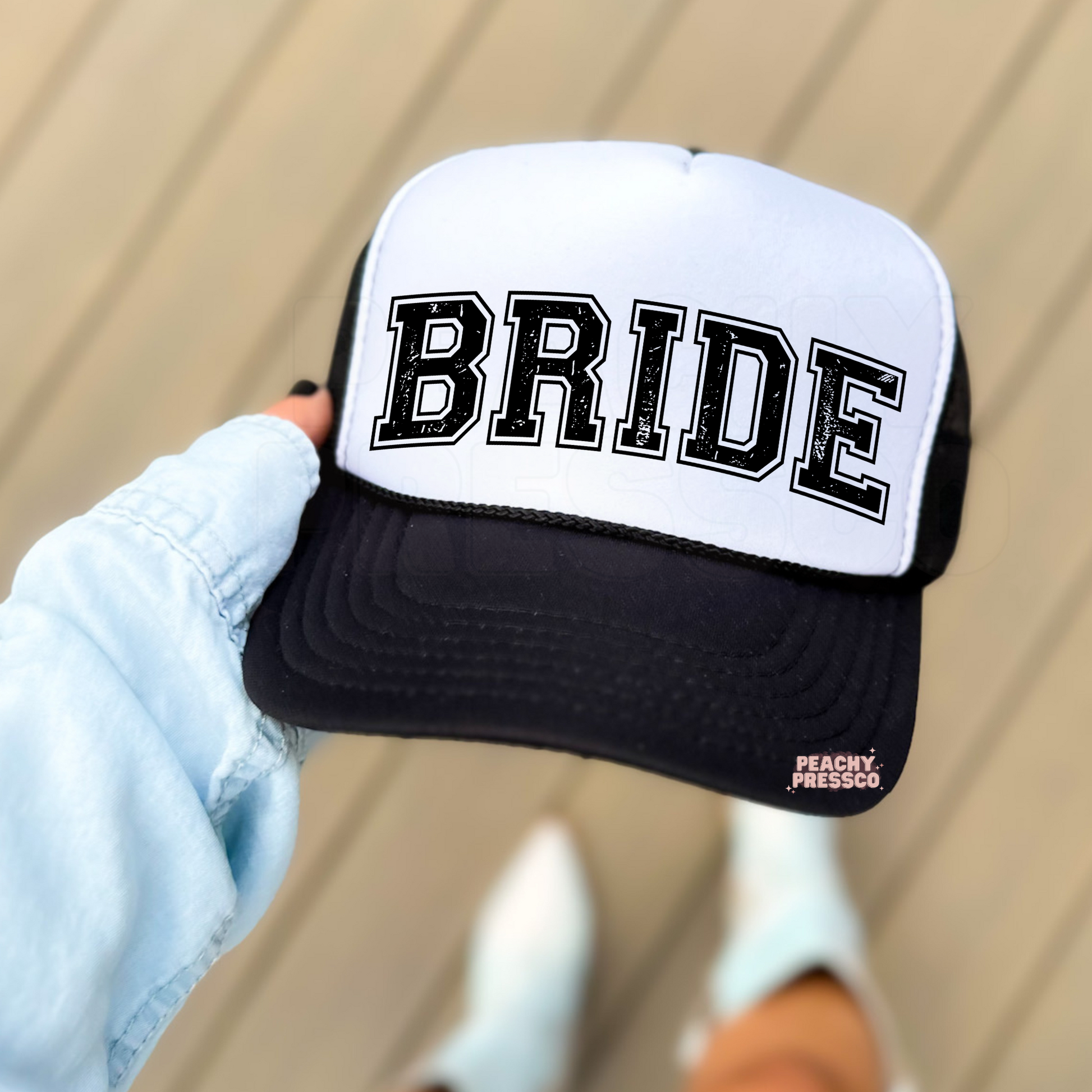 White and black foam trucker hat featuring distressed "BRIDE" collegiate lettering, trendy bridal hat for the bride-to-be, bachelorette weekends, bridal showers, and weddings.