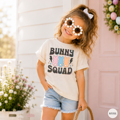 Girl wearing a natural Bunny Squad Easter shirt with colorful bunny and retro spring graphic.