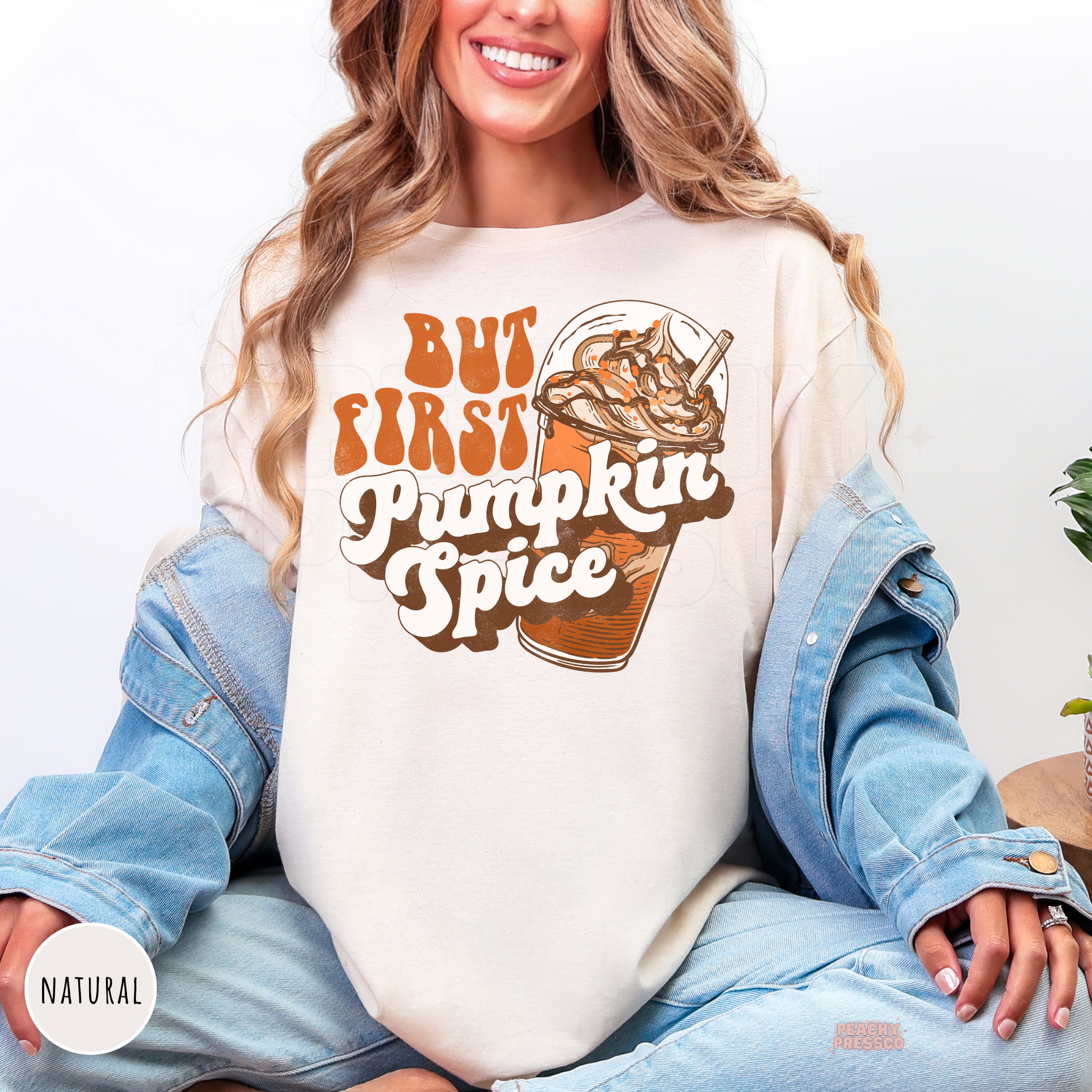 Woman wearing a natural shirt with a retro But First Pumpkin Spice graphic featuring a vintage iced pumpkin spice drink.