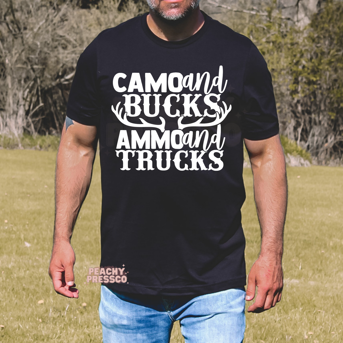 Black t-shirt featuring the bold white "Camo and Bucks Ammo and Trucks" hunting graphic with deer antlers. Perfect for hunters, outdoorsmen, truck enthusiasts, and country living.