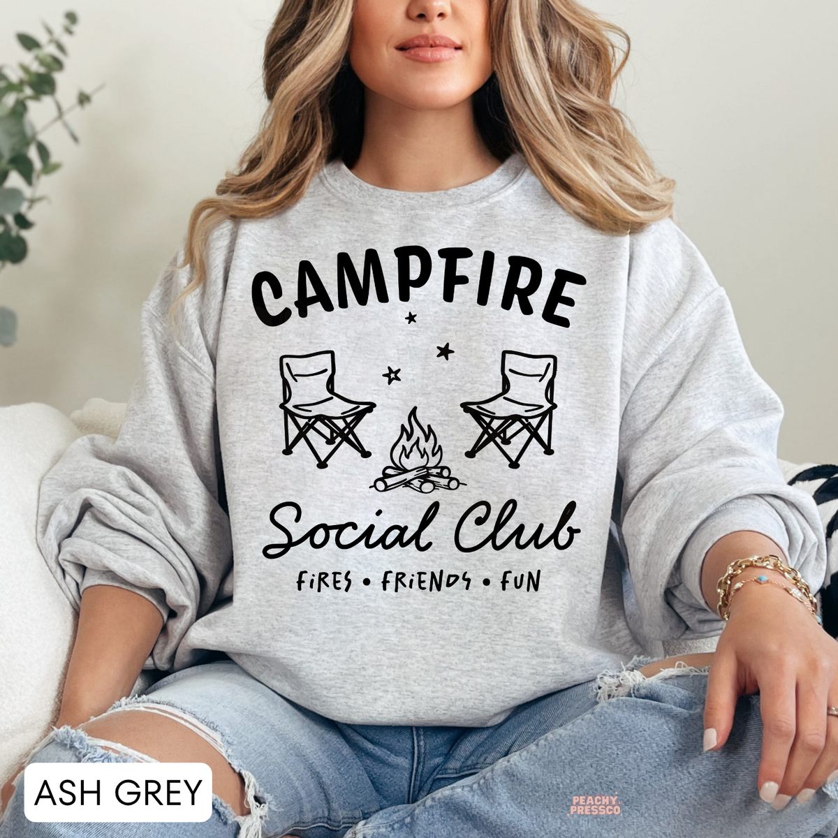 Ash grey Campfire Social Club sweatshirt featuring a minimalist bonfire, camping chairs and Fires Friends Fun graphic.