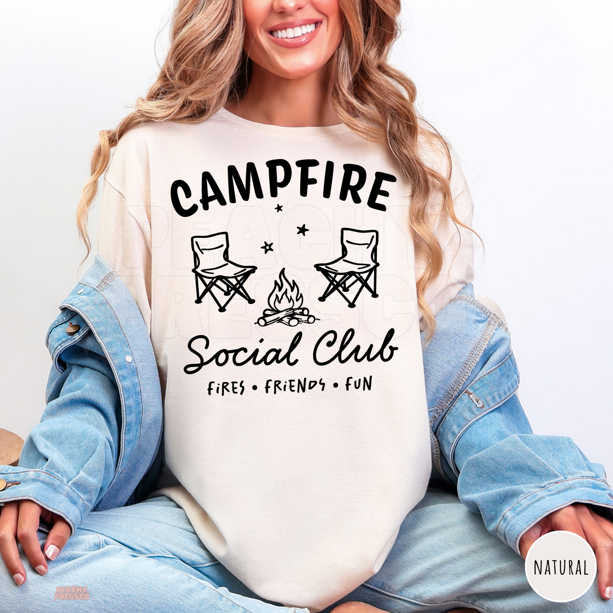 Campfire Social Club natural shirt featuring two camping chairs, a cozy bonfire, stars and Fires Friends Fun lettering.
