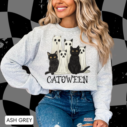 Woman wearing an ash grey crewneck sweatshirt featuring a cute Catoween design with black cats, ghost cats and spooky Halloween artwork.
