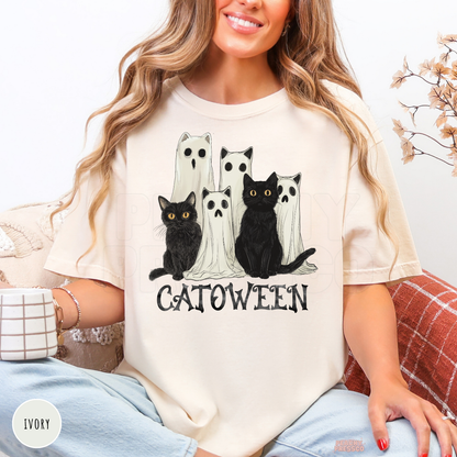 Woman wearing an ivory Comfort Colors t-shirt featuring a Catoween black cat and ghost cat Halloween graphic.