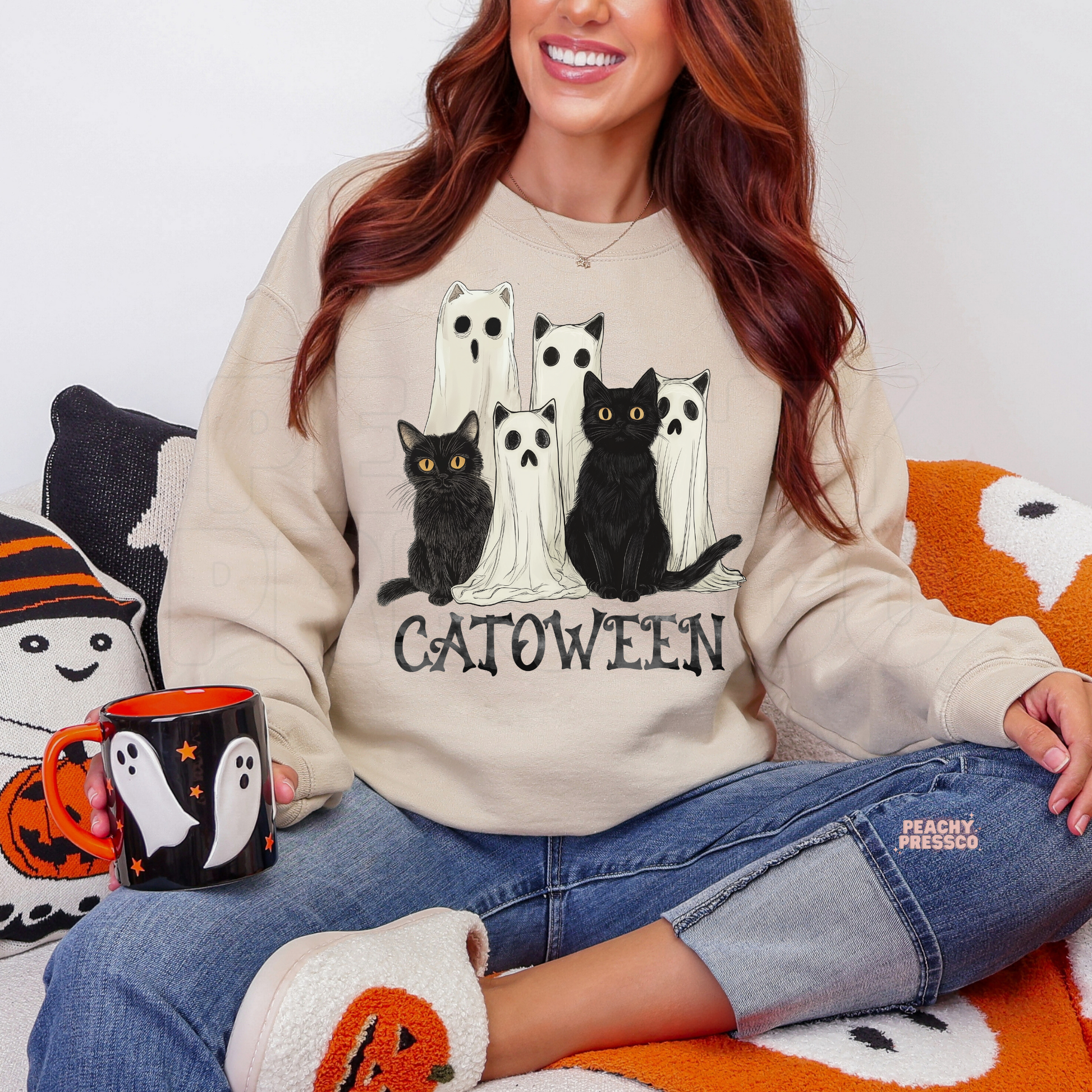 Woman wearing a sand crewneck sweatshirt featuring a Catoween design with black cats, ghost cats and spooky Halloween artwork.