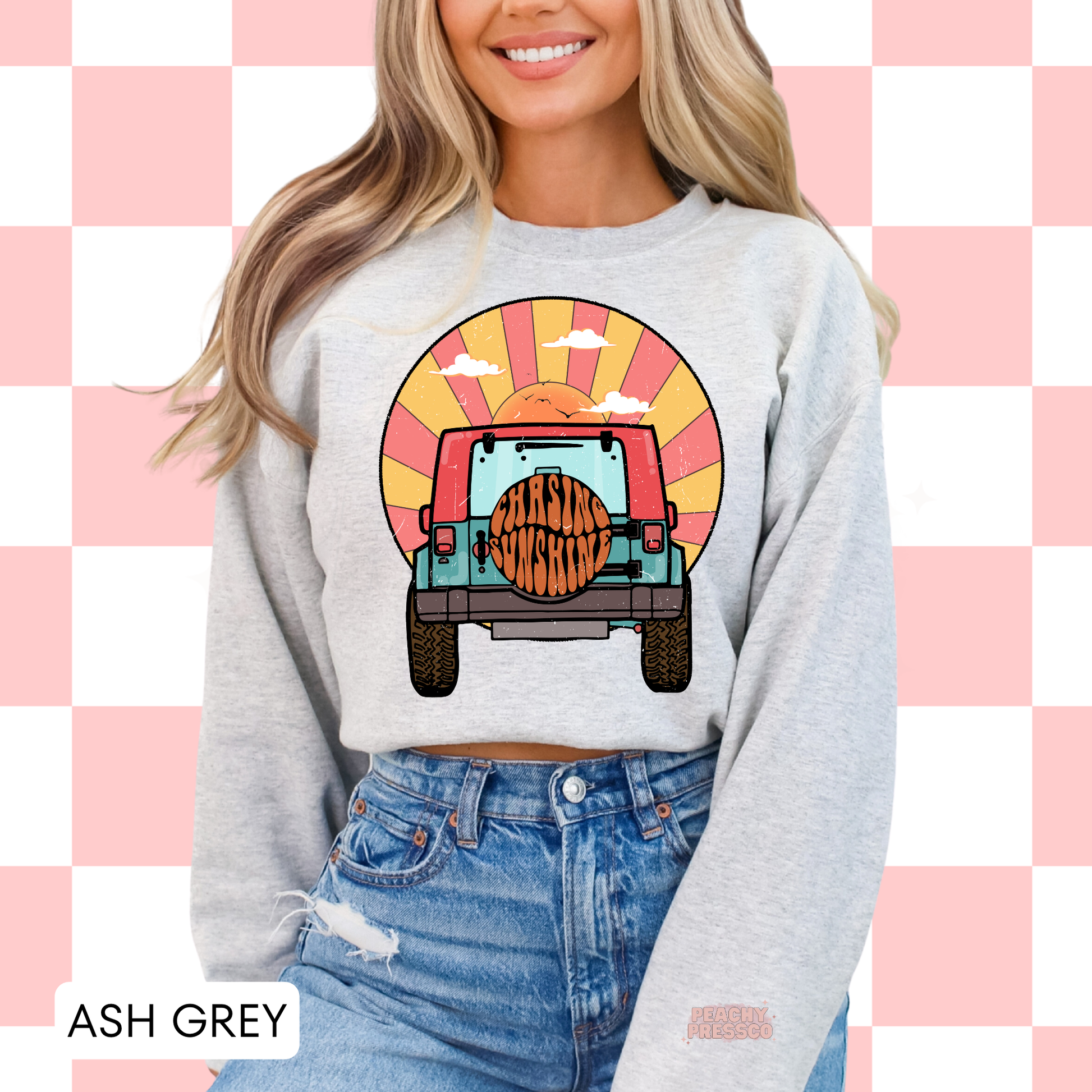 Ash Grey Gildan crewneck sweatshirt featuring a retro off-road vehicle and sunset graphic with "Chasing Sunshine" on the spare tire. Classic unisex sweatshirt inspired by beach vacations, camping, road trips, and laid-back outdoor adventures.