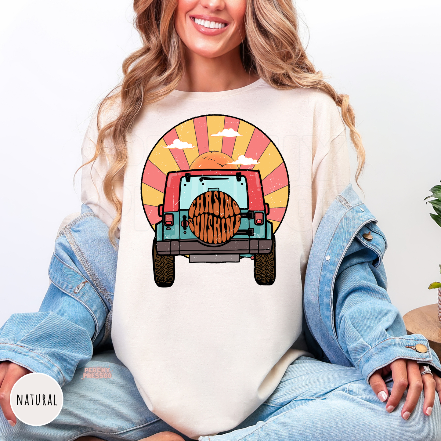 Natural Gildan unisex t-shirt featuring a retro off-road vehicle driving toward a colorful sunset with "Chasing Sunshine" on the spare tire. Vintage-inspired beach graphic with warm sunset tones, perfect for summer, lake days, camping, road trips, and outdoor adventures.