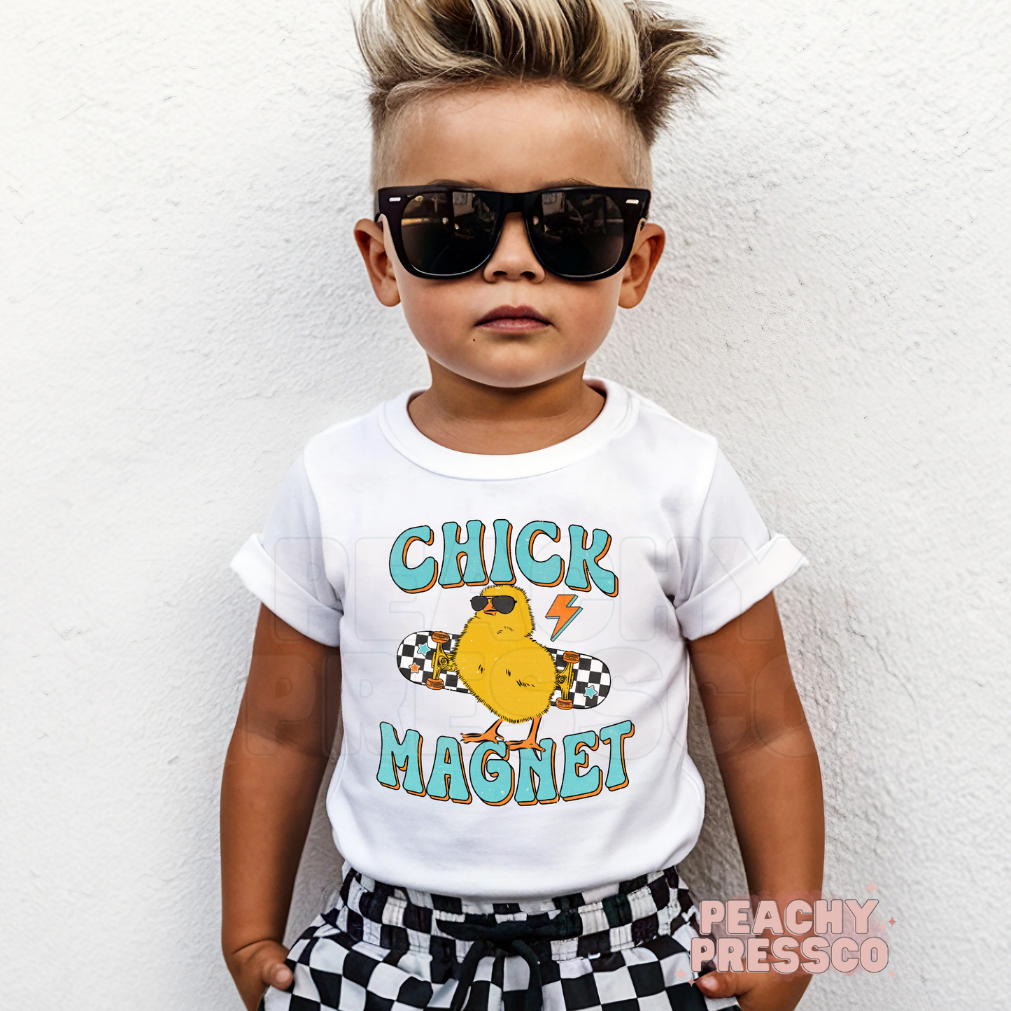 Toddler boy wearing a white Chick Magnet Easter shirt with a retro skateboard chick graphic and playful Easter theme.