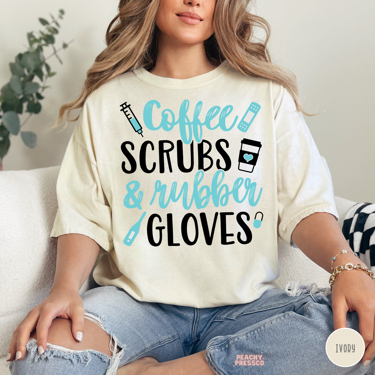 Woman modeling an ivory Coffee Scrubs & Rubber Gloves graphic T-shirt with turquoise medical illustrations and bold black lettering.