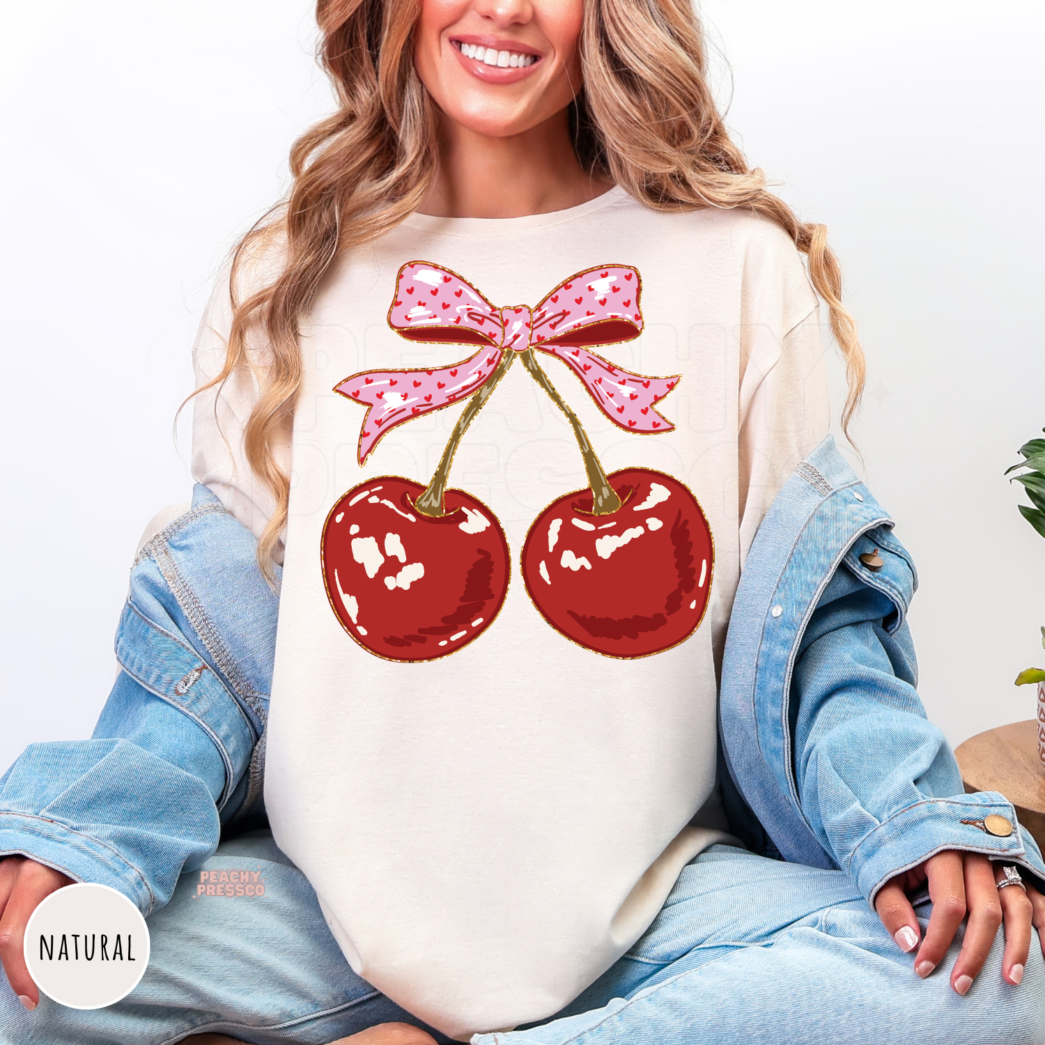 Natural shirt with a coquette cherry design featuring glossy red cherries and a pink bow, cute vintage-inspired aesthetic sweatshirt.