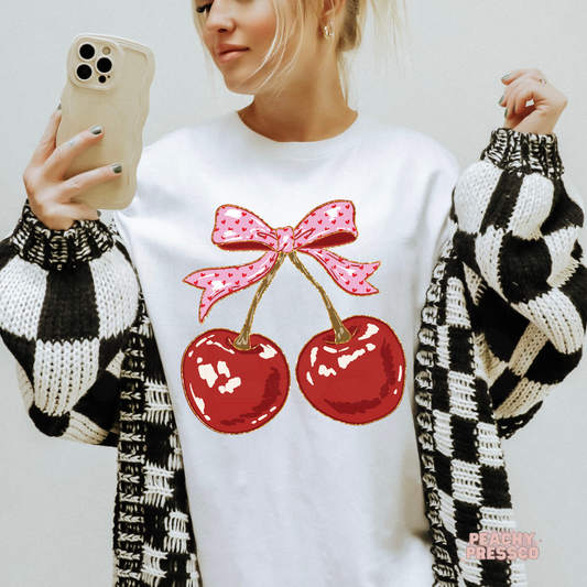 White crewneck sweatshirt with a cute cherry and pink bow graphic, trendy coquette aesthetic women's sweatshirt.