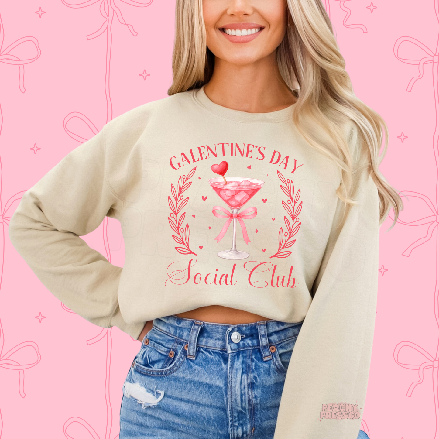 Sand sweatshirt displaying a Galentine's Day Social Club design with a pink cocktail glass, heart pick, ribbon bow, and elegant Valentine's artwork.