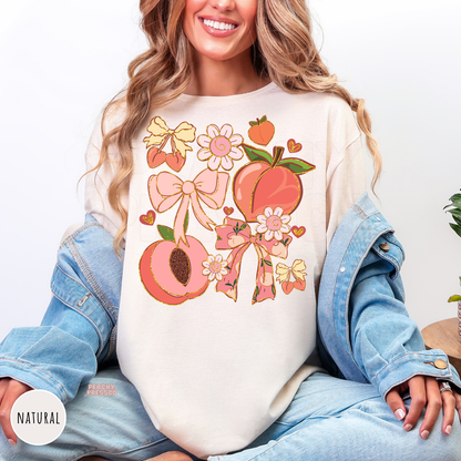 Natural Comfort Colors t-shirt featuring a pastel peach, bow, flower, and cherry collage with coquette-inspired artwork for a cute cottagecore summer style.
