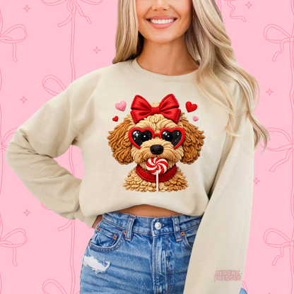 Sand crewneck sweatshirt featuring a coquette-style Valentine's puppy with heart glasses, a red bow, and a peppermint candy.