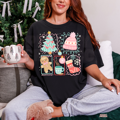 Woman sitting cross-legged holding a holiday mug wearing a black graphic t-shirt printed with cozy Christmas collage icons like a tree, beanie, and gingerbread man.