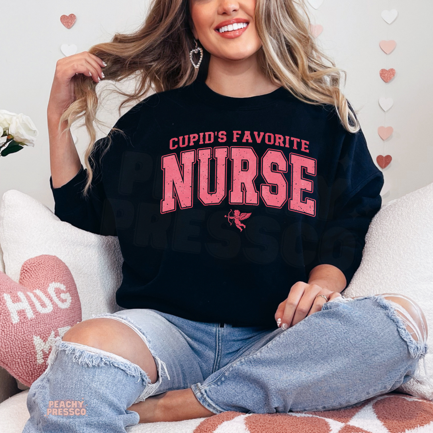 Black sweatshirt showcasing a distressed pink "Cupid's Favorite Nurse" graphic with Cupid, ideal for nurses celebrating Valentine's Day.