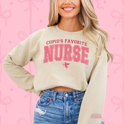 Sand sweatshirt featuring a vintage pink "Cupid's Favorite Nurse" design with varsity lettering and Cupid for a festive Valentine's look.