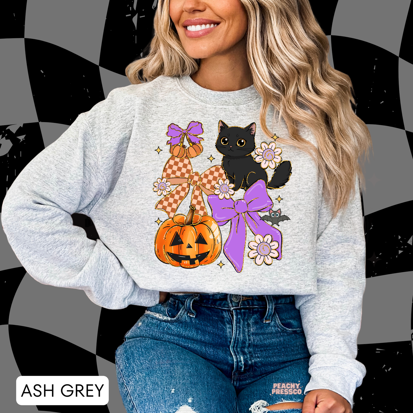 Woman wearing an ash grey crewneck featuring a cute black cat, jack-o'-lantern pumpkin, purple bows, flowers and bat Halloween graphic.