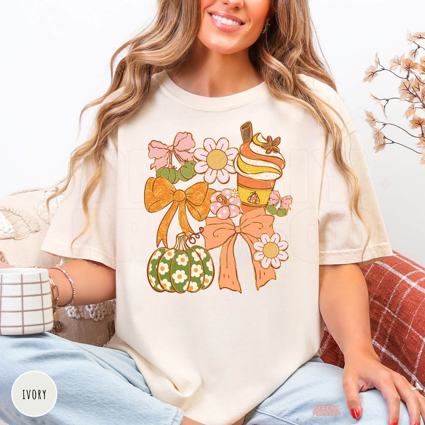 Woman wearing an ivory graphic t-shirt with a coquette fall design featuring bows, a pumpkin spice latte, floral pumpkin, daisies, and pastel autumn aesthetic artwork.