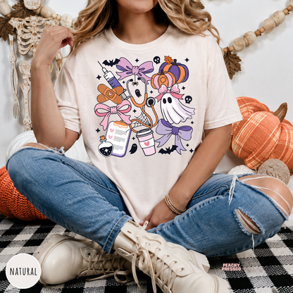 Woman wearing a natural Comfort Colors t-shirt with a cute Halloween nurse design featuring ghosts, pumpkins, stethoscope and medical icons.