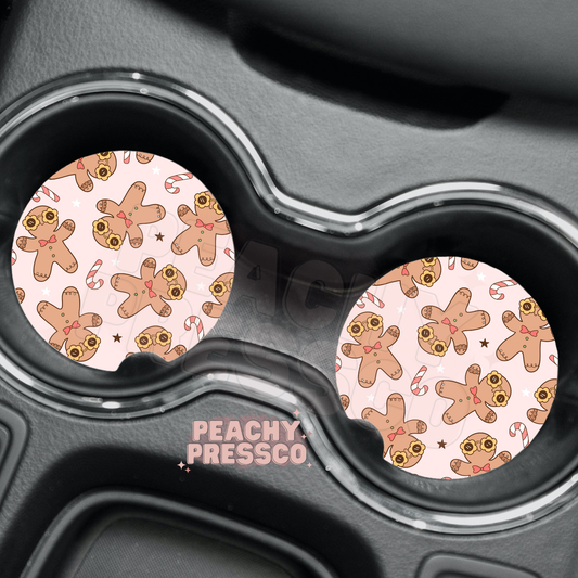 Pair of pink car cup holder coasters featuring cute gingerbread men wearing flower sunglasses with candy canes.