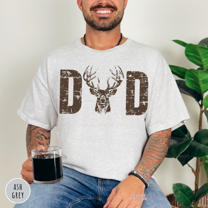 Ash Grey t-shirt featuring a distressed "DAD" deer hunting design with a large buck head graphic. A thoughtful Father's Day gift for hunters, dads, and outdoor adventure lovers.
