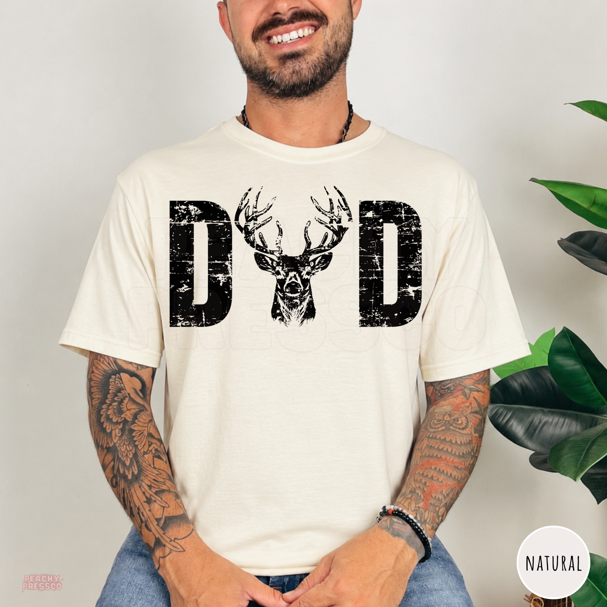 Natural t-shirt featuring a distressed "DAD" graphic with a realistic buck deer head. Perfect gift for dads who enjoy deer hunting, camping, fishing, and the outdoors.