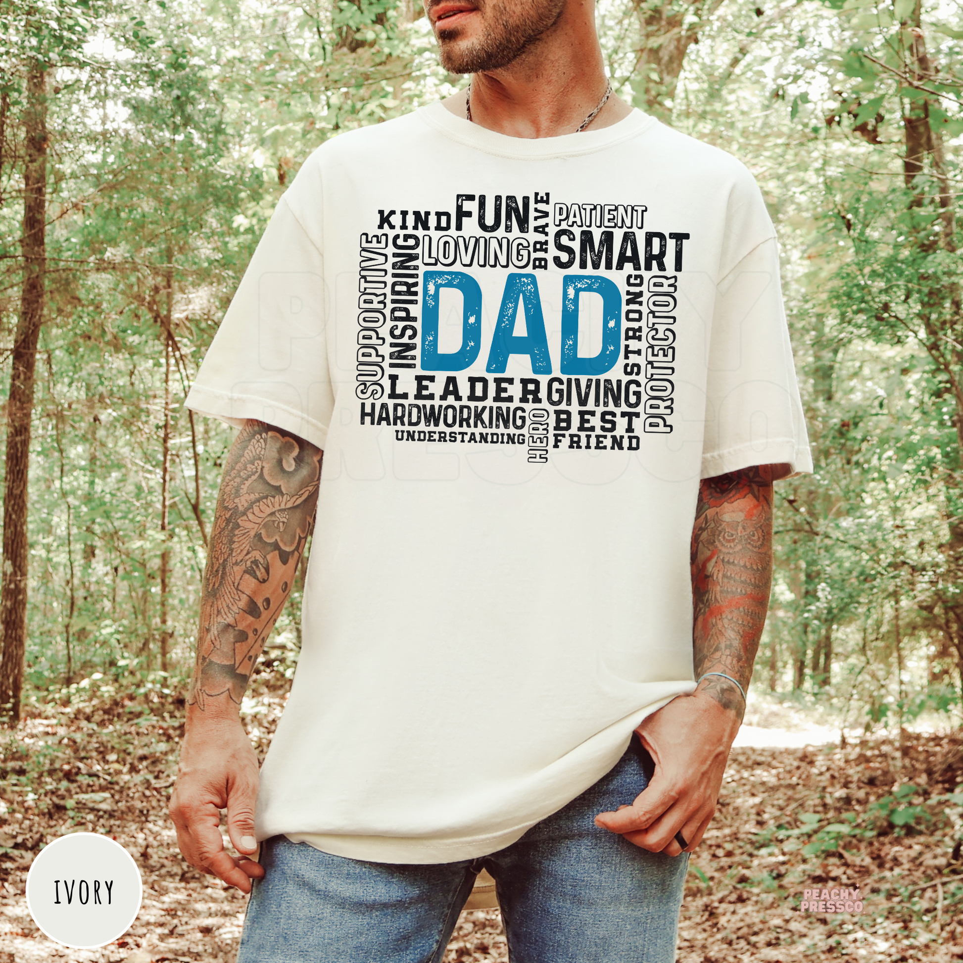 Ivory Comfort Colors style t-shirt with a blue "Dad" word cloud design highlighting qualities like kind, patient, strong, loving, protector, and best friend. Perfect gift for fathers.